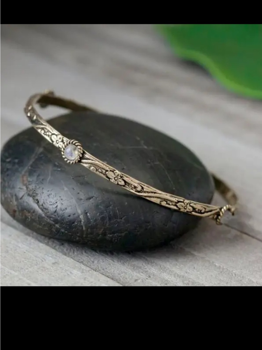Decorated brass bangle featuring four moonstones.